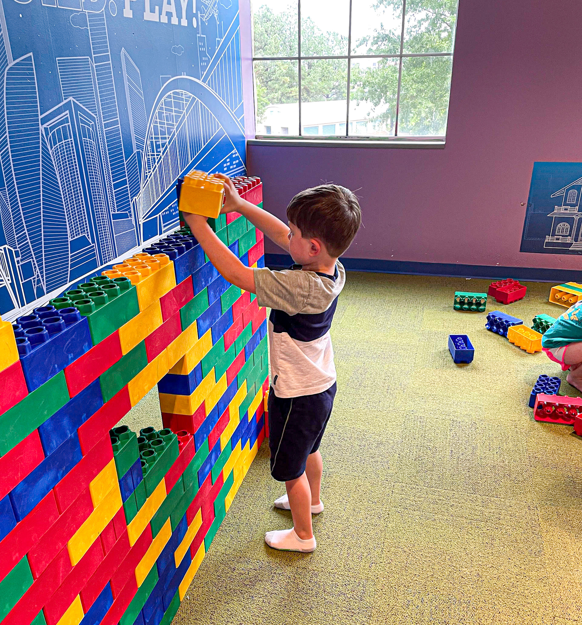 A little boy playing with large legos at a children's museum.