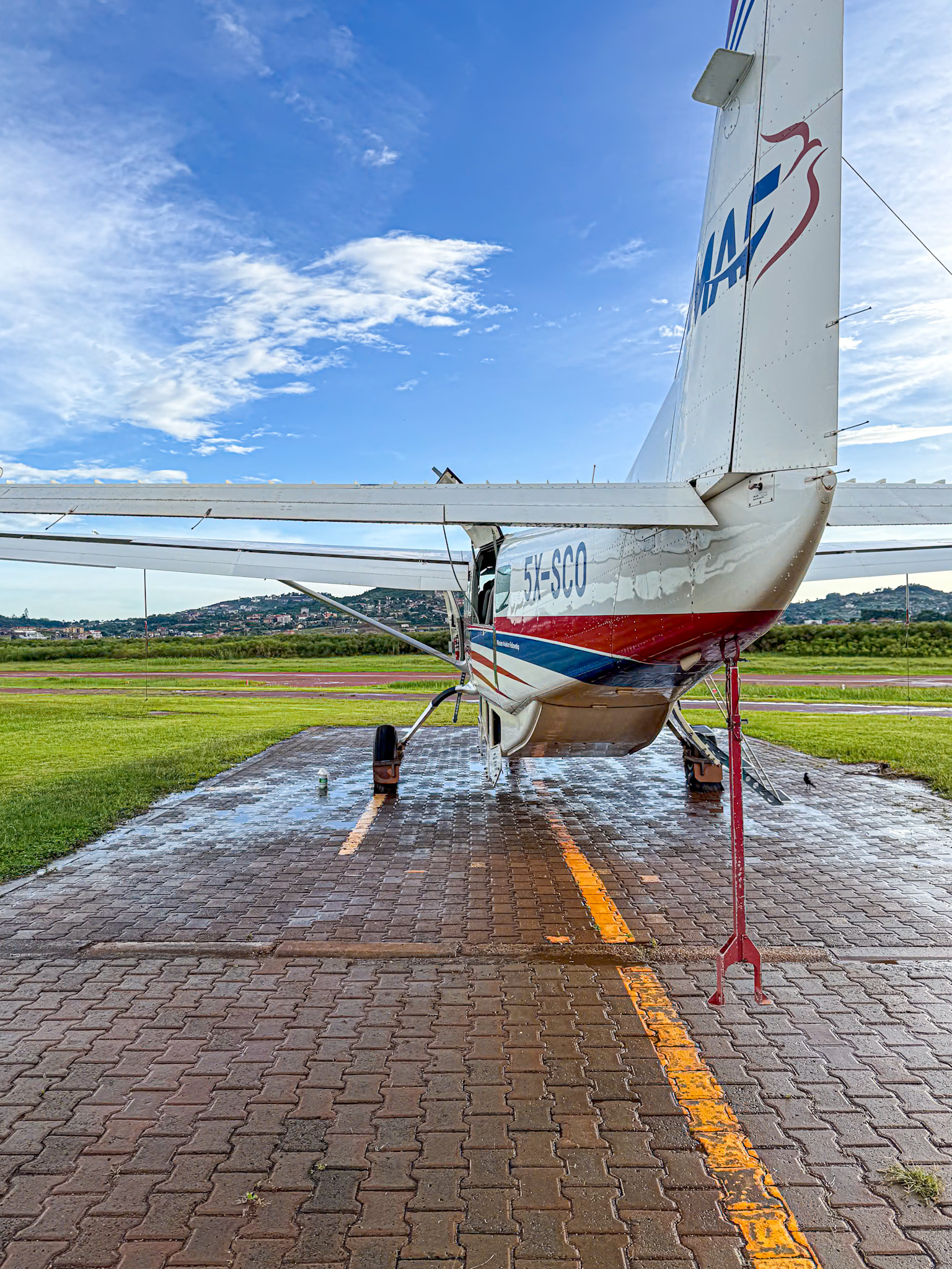 A small plane parked in an airfield in Uganda with blue skies on a beautiful day. 