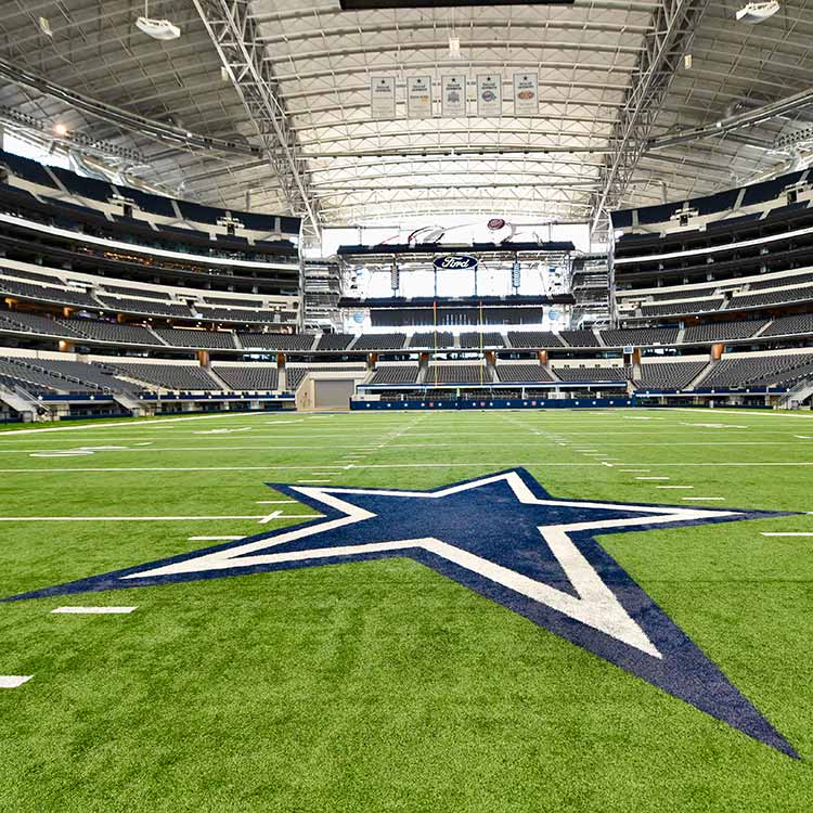 Interior view of the empty Dallas Cowboys football stadium with a large blue star logo at the center of the field.