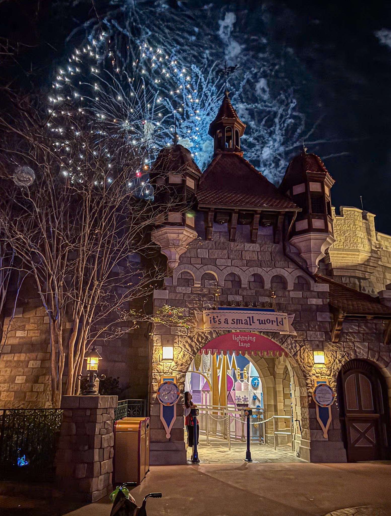 Fireworks light up the night sky above the its a small world entrance at a theme park.