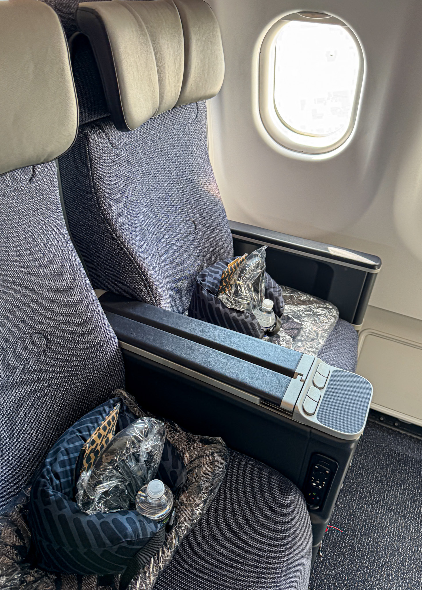 Two Finnair Premium Economy airplane seats by a window, with amenities and bottled water placed on each seat.