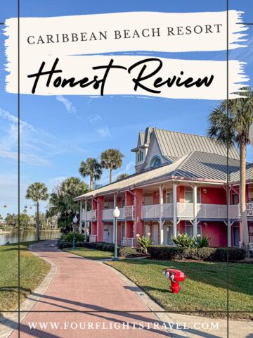 A pink resort building with palm trees and a clear blue sky at Caribbean Beach Resort.