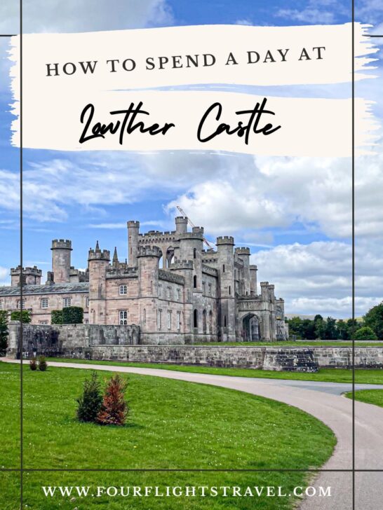 Large stone castle with towers and arches, surrounded by green lawns under a partly cloudy sky.