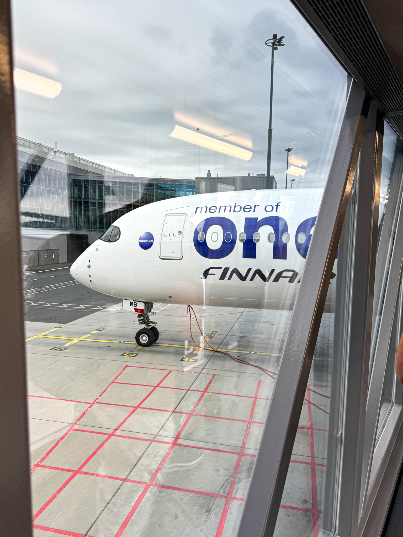 Finnair aircraft at airport gate as seen from inside the terminal near a boarding bridge.