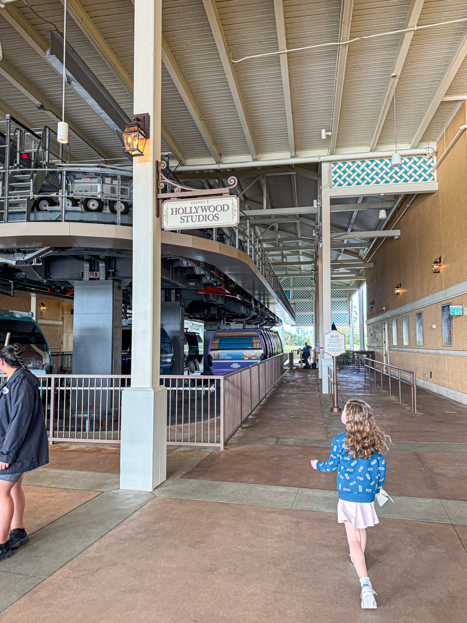 A young girl walks toward the Disney Skyliner at the Hollywood Studios station.