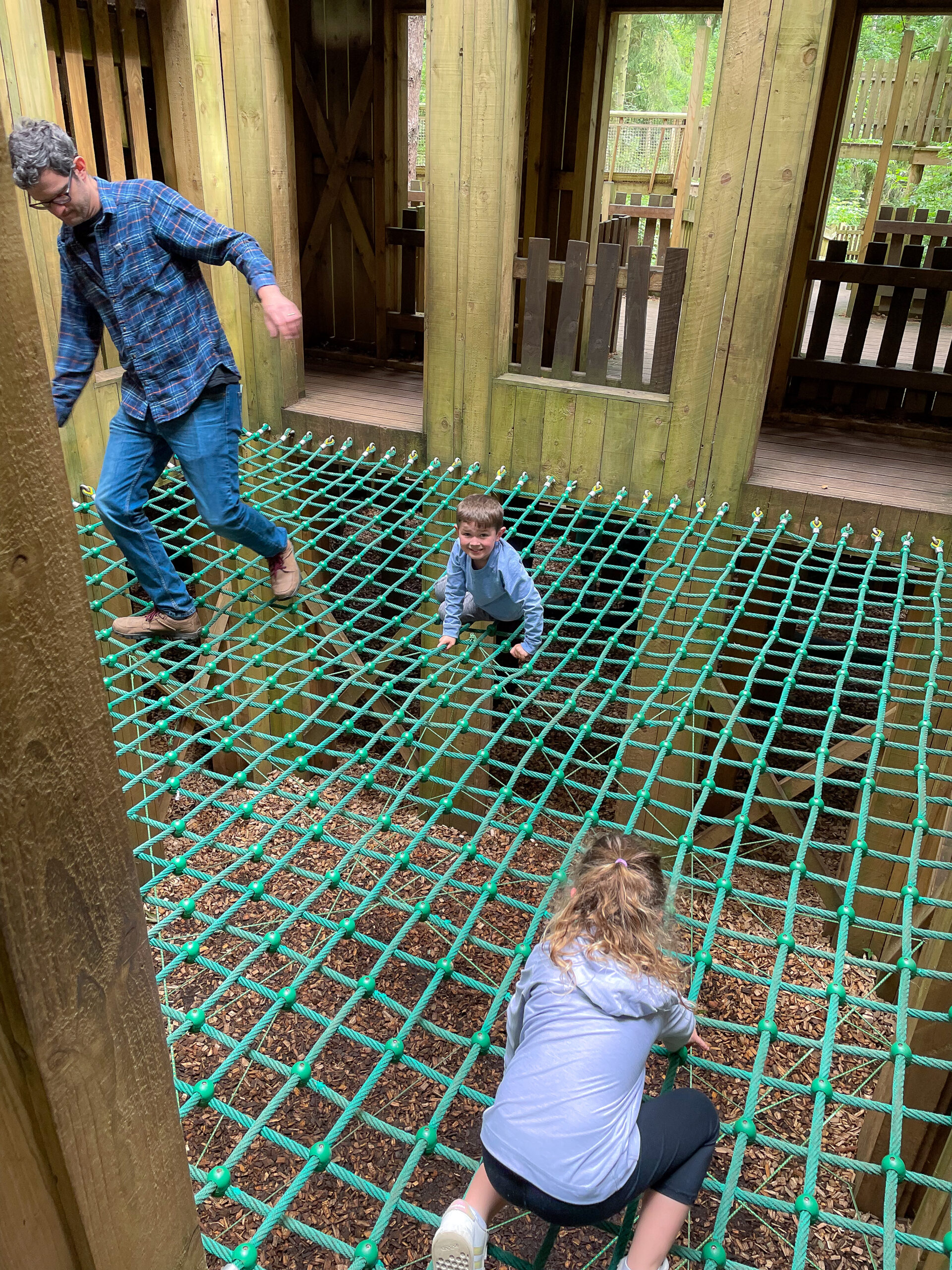 A man and a boy playing on a rope net.
