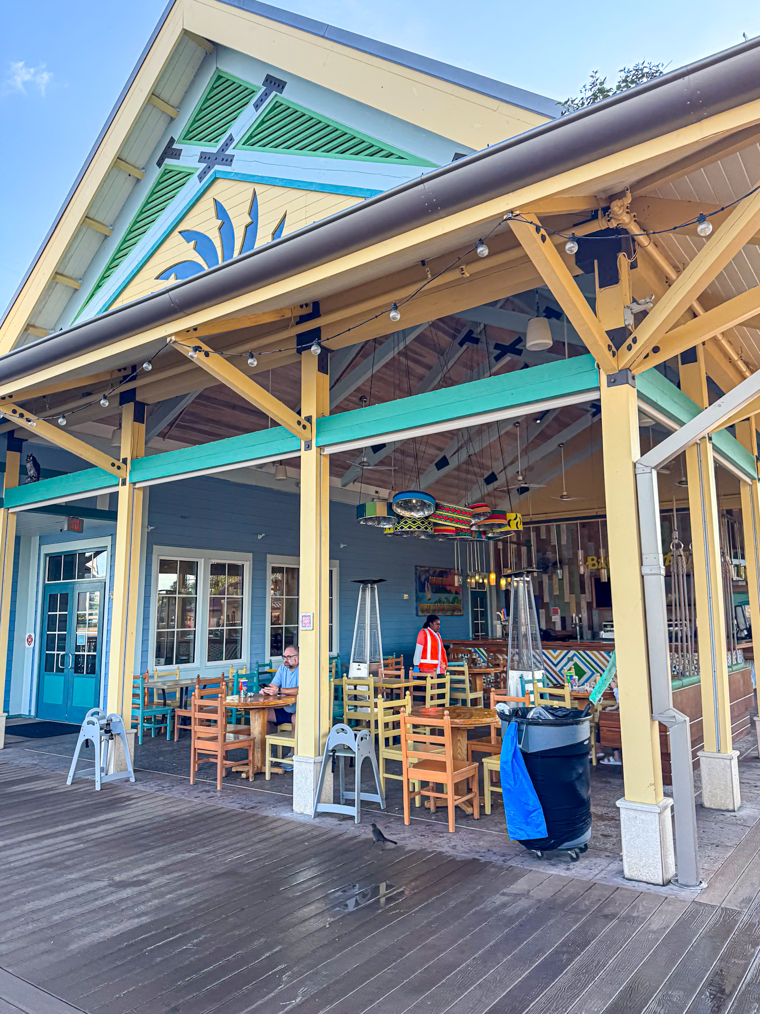 Outdoor seating area at Banana Cabana with wooden tables, chairs, and a covered roof.