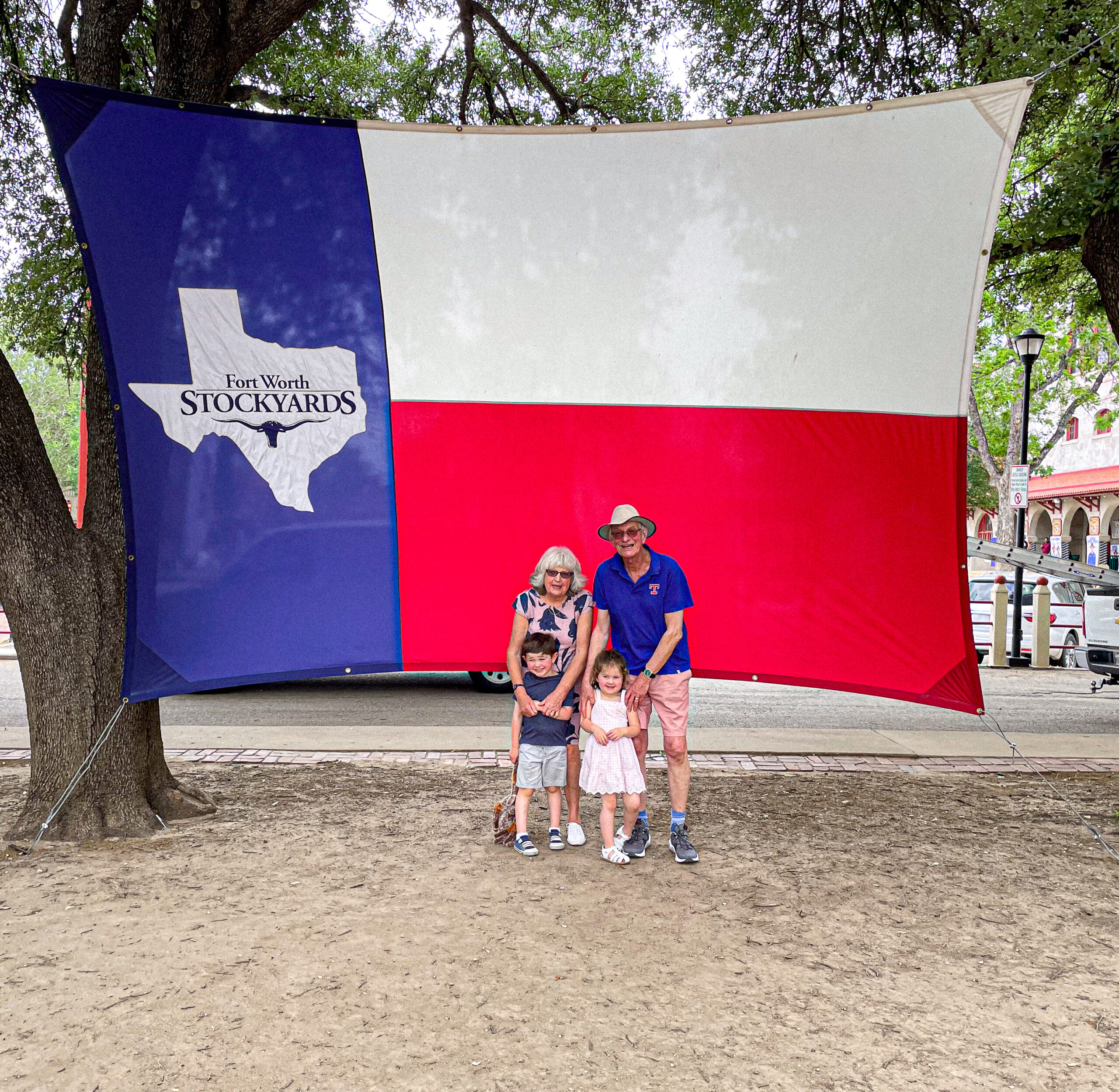 A family poses in front of a large Texas flag at the Fort Worth Stockyards.