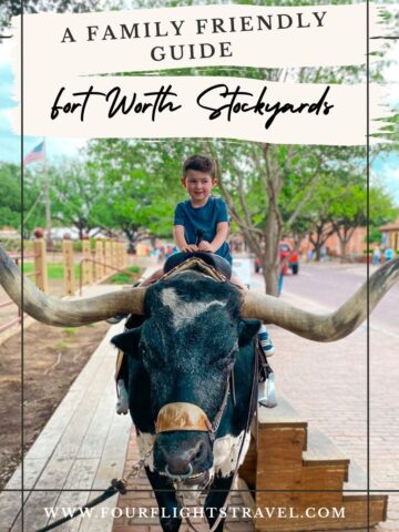 Young boy sitting on a longhorn statue at Fort Worth Stockyards, with a family-friendly travel guide sign.