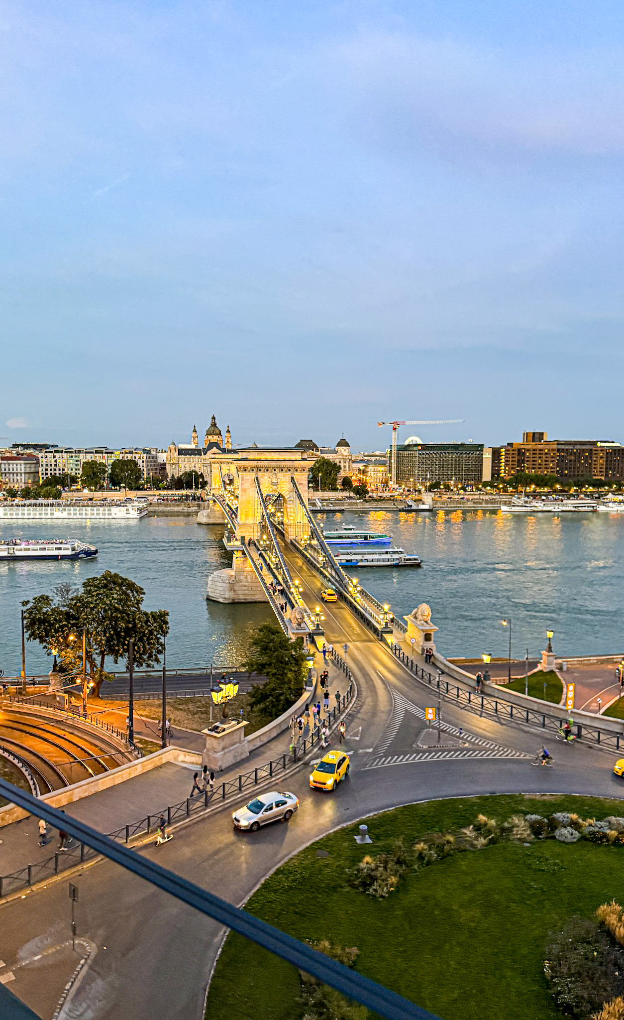 Aerial view of the Chain Bridge over the Danube River in Budapest at sunset, with cars and pedestrians, from the Hotel Clark.