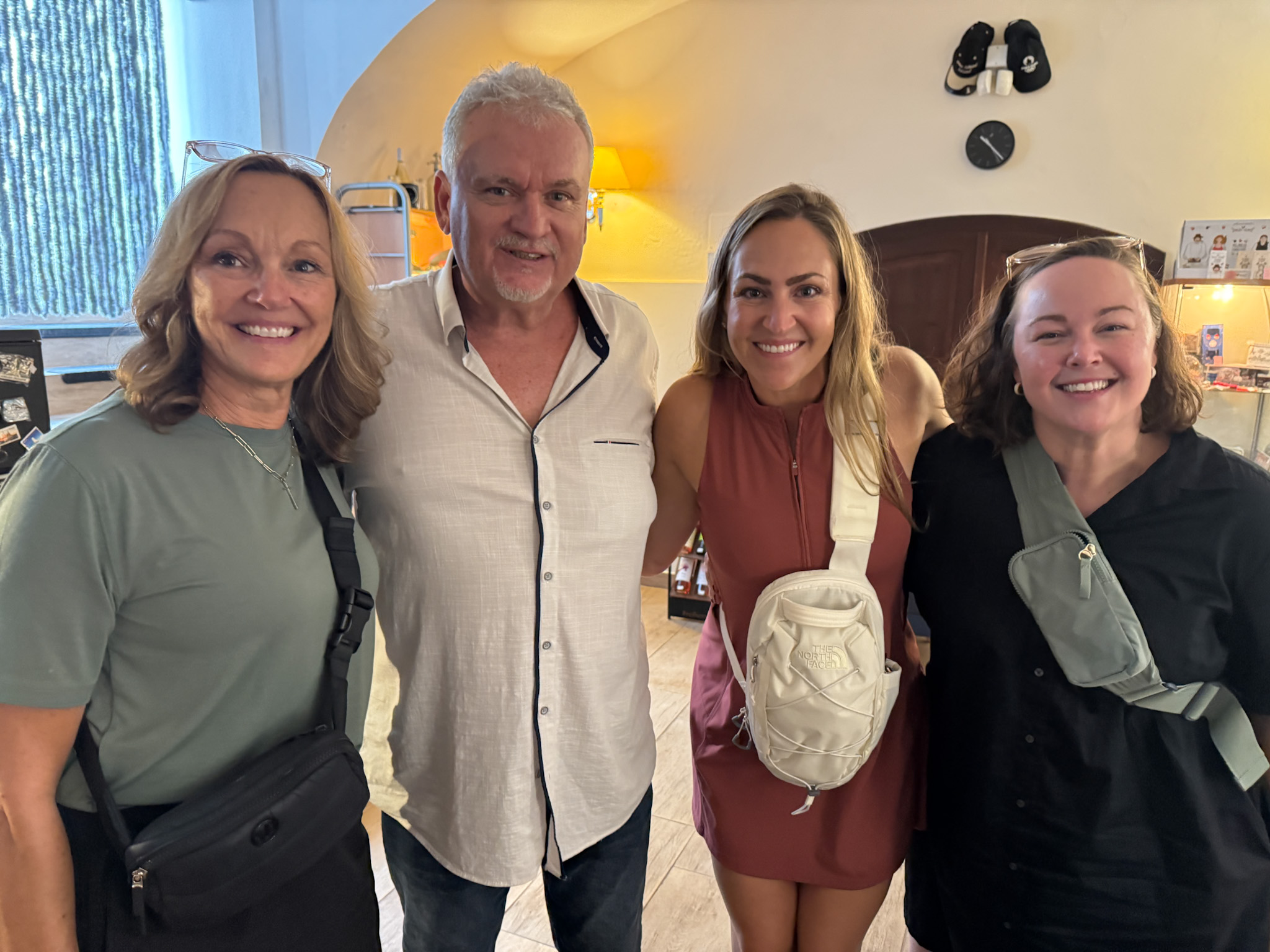 Four adults smiling and standing together indoors, posing for a group photo with casual outfits and crossbody bags at the Secret Budapest food tour.